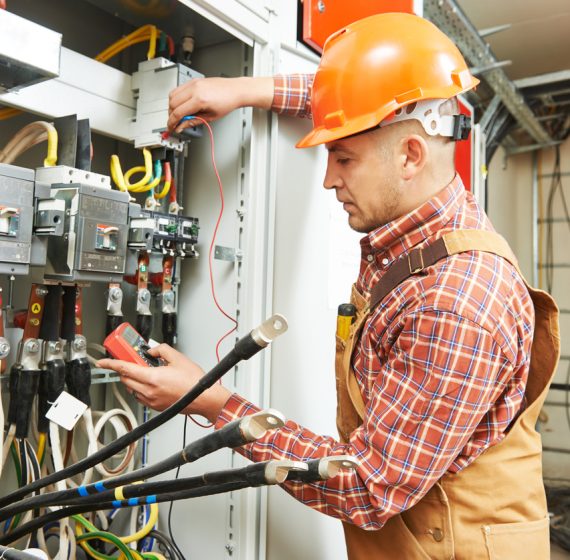 young adult electrician builder engineer worker in front of fuse switch board